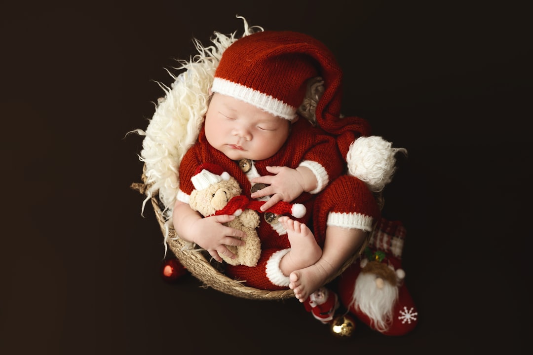 A baby wearing a santa hat and holding a teddy bear