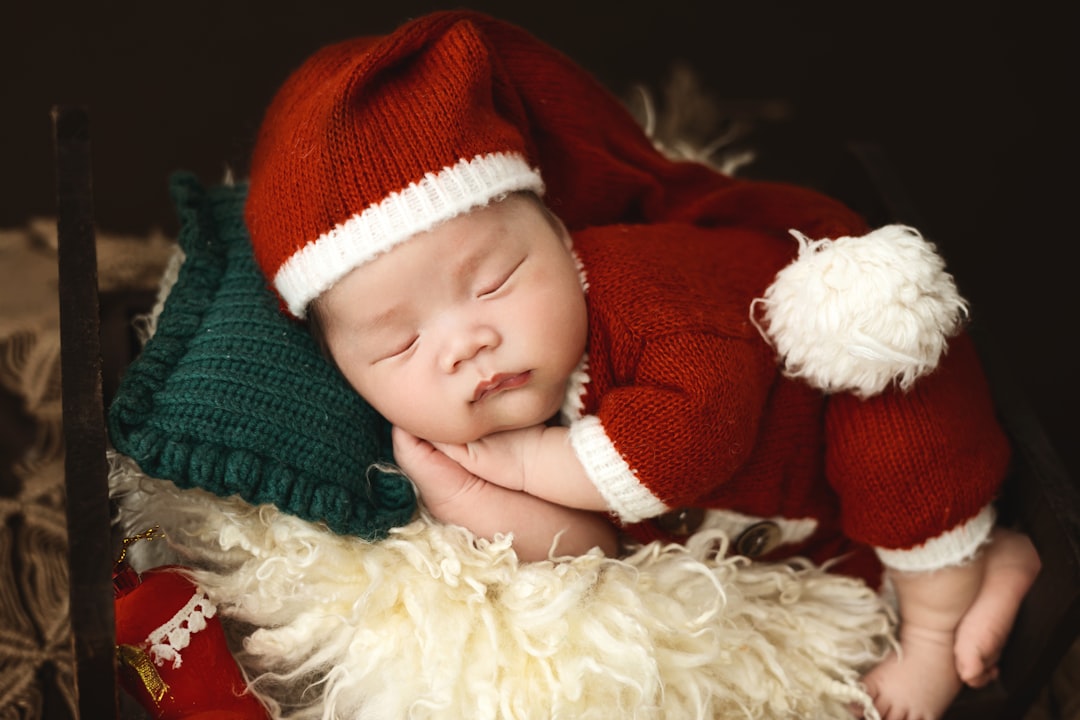 A baby wearing a santa hat sleeping on top of a stuffed animal