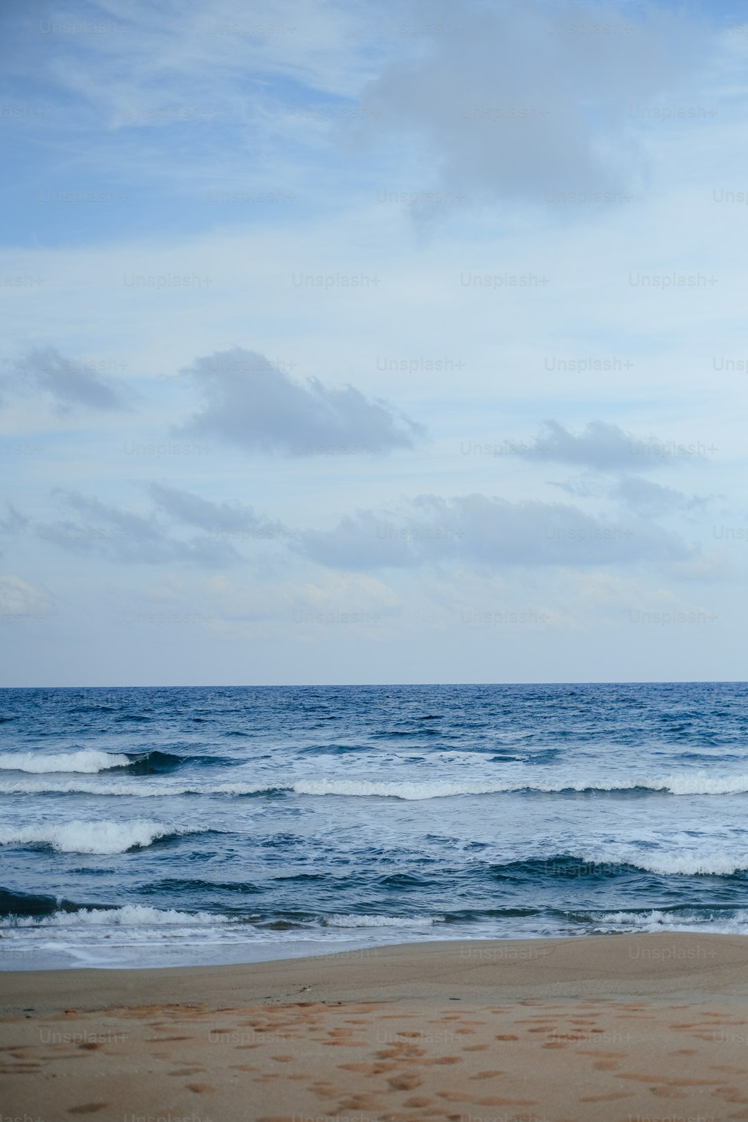 a beach with waves and clouds