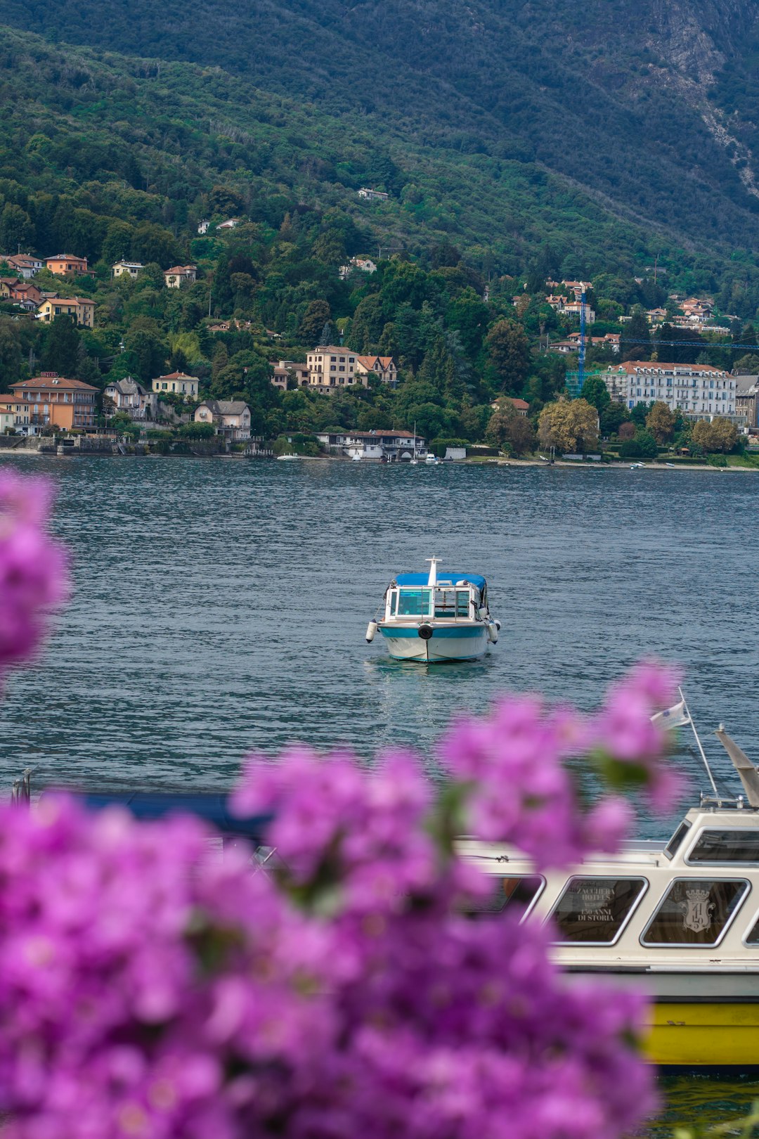 A boat floating on top of a lake next to a lush green hillside