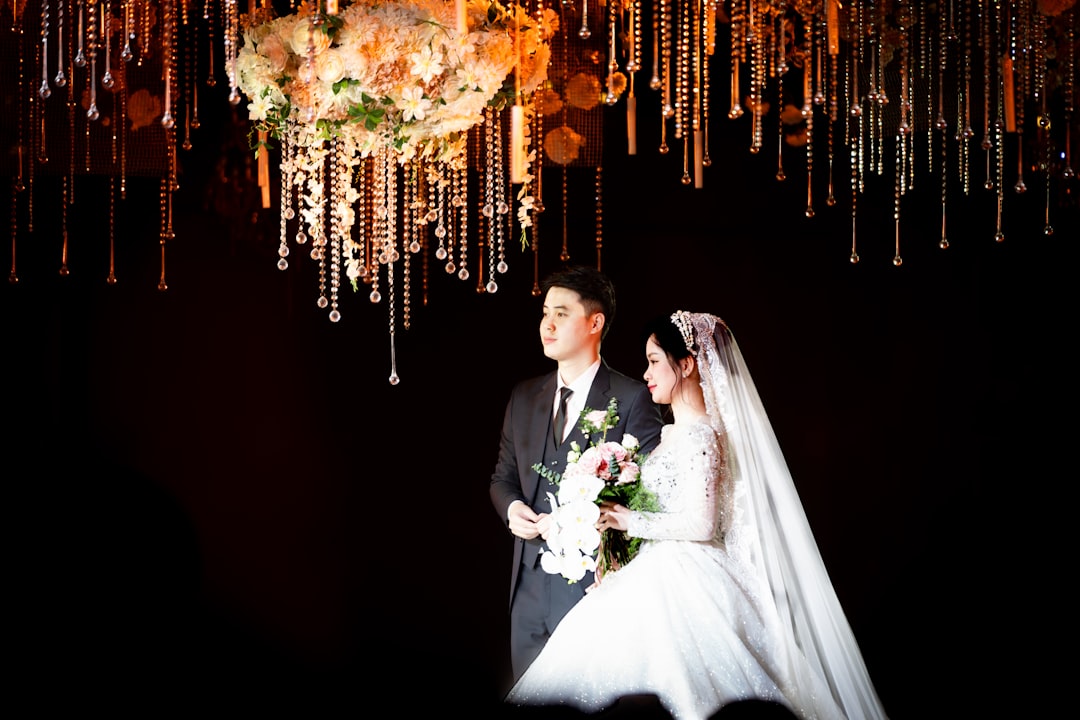 A bride and groom standing under a chandelier