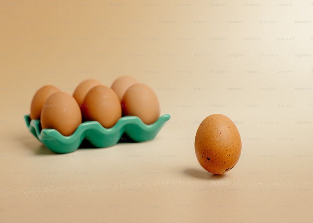 A carton of eggs sitting next to a brown egg