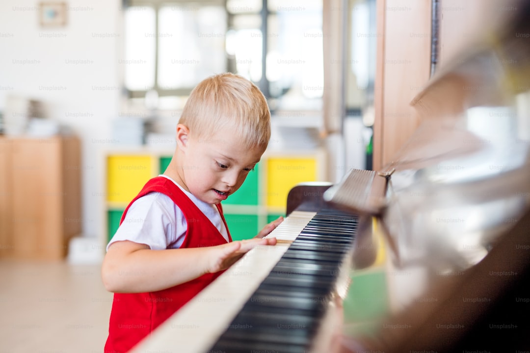 A cheerful down-syndrome school boy sitting at school, playing piano.