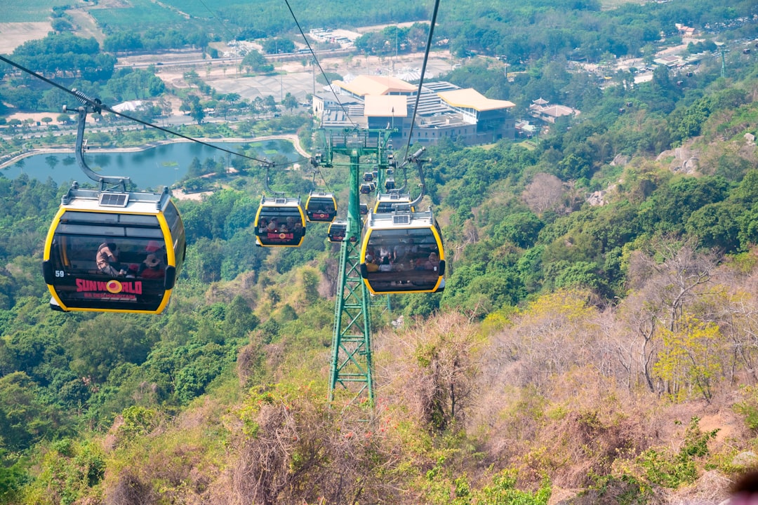 a couple of people riding a cable car over a lush green hillside