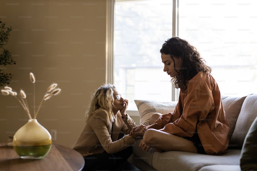 a couple of women sitting on top of a couch