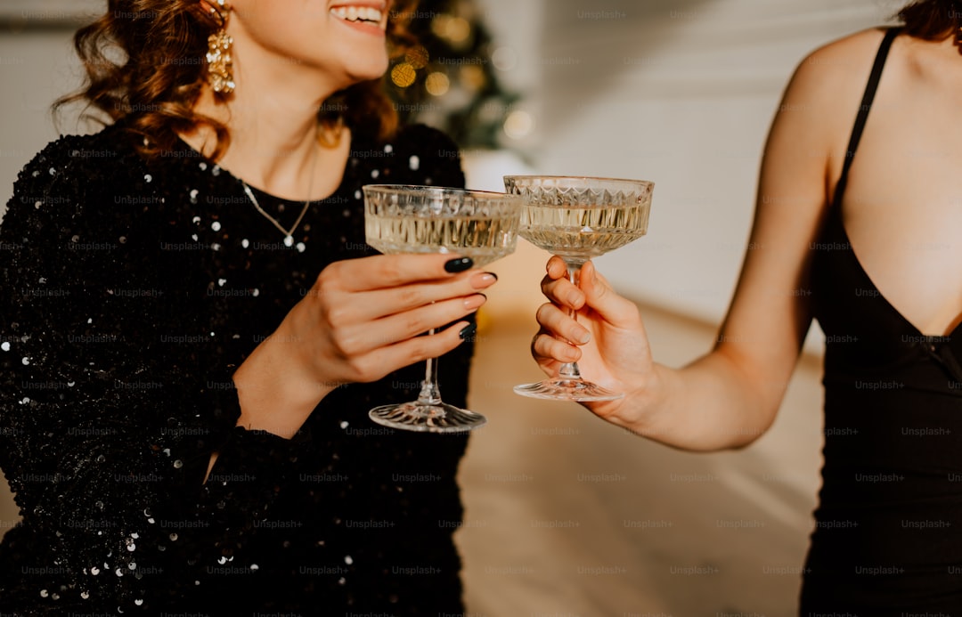 a couple of women standing next to each other holding wine glasses