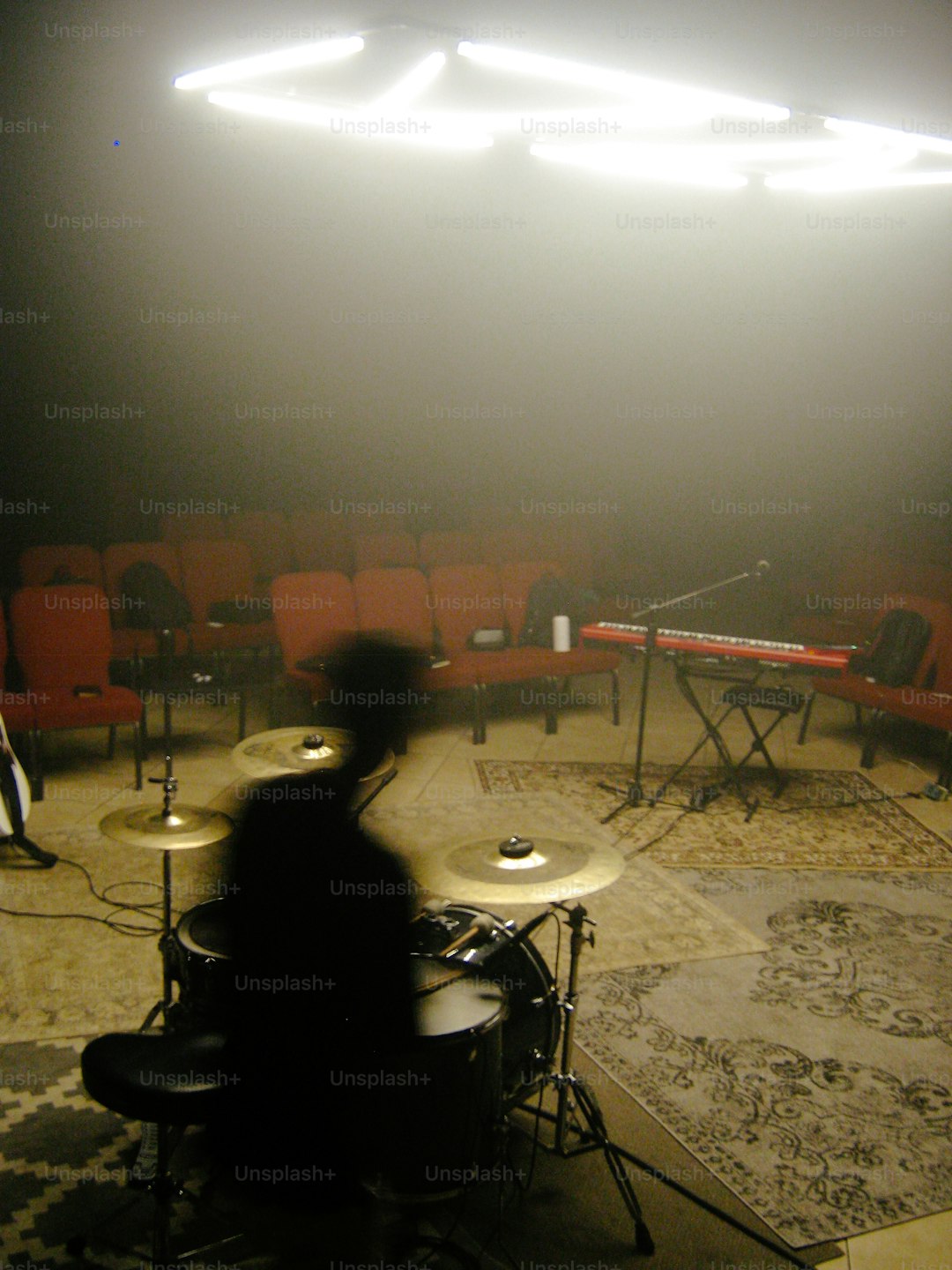 A drummer plays in a dimly lit venue.