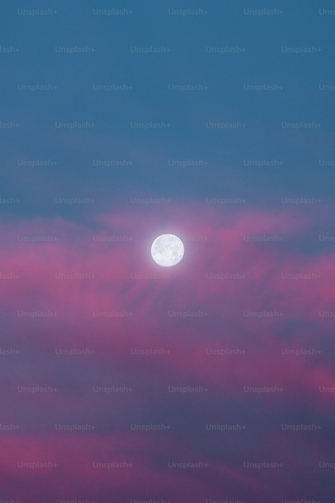 A full moon is seen in the sky with pink clouds