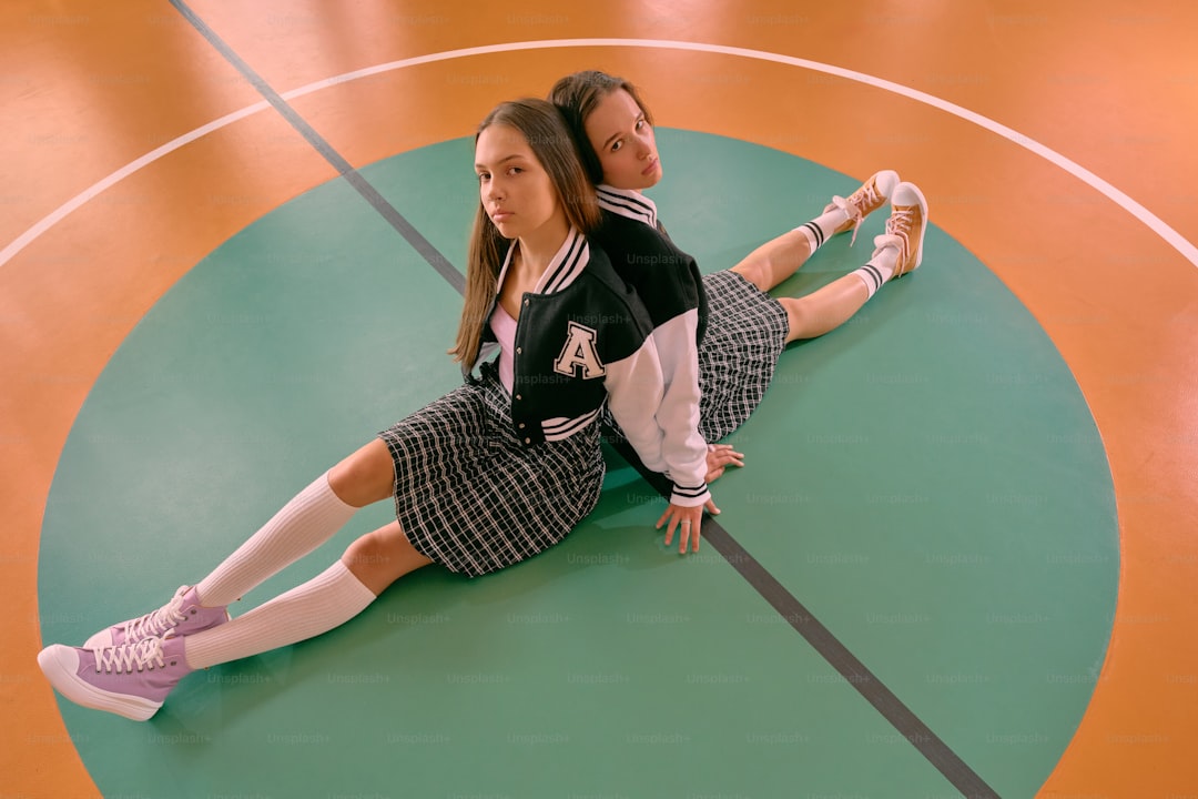 A girl sitting on a basketball court with her legs crossed