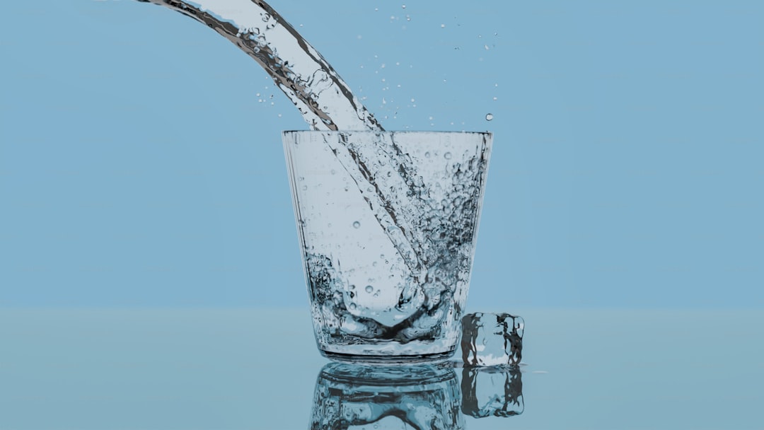 A glass filled with water with a blue background