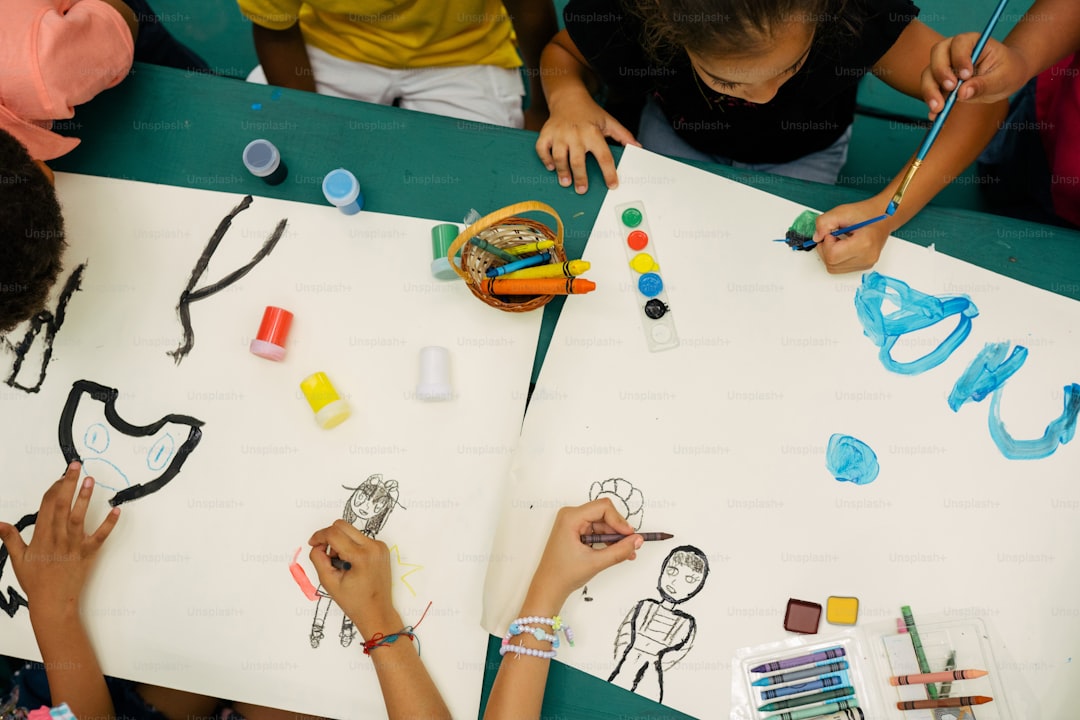 a group of children sitting at a table drawing on paper