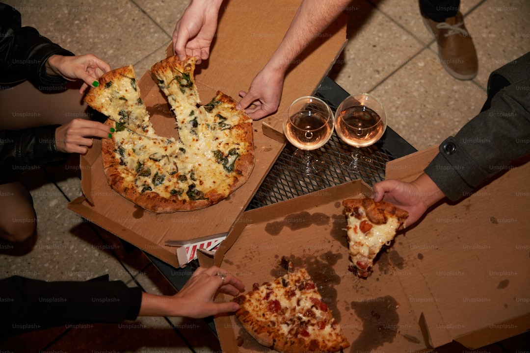 a group of people grabbing slices of pizza