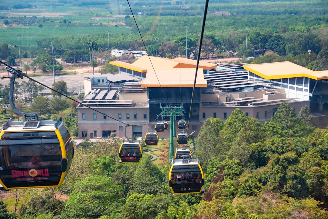 a group of people riding a cable car over a lush green forest