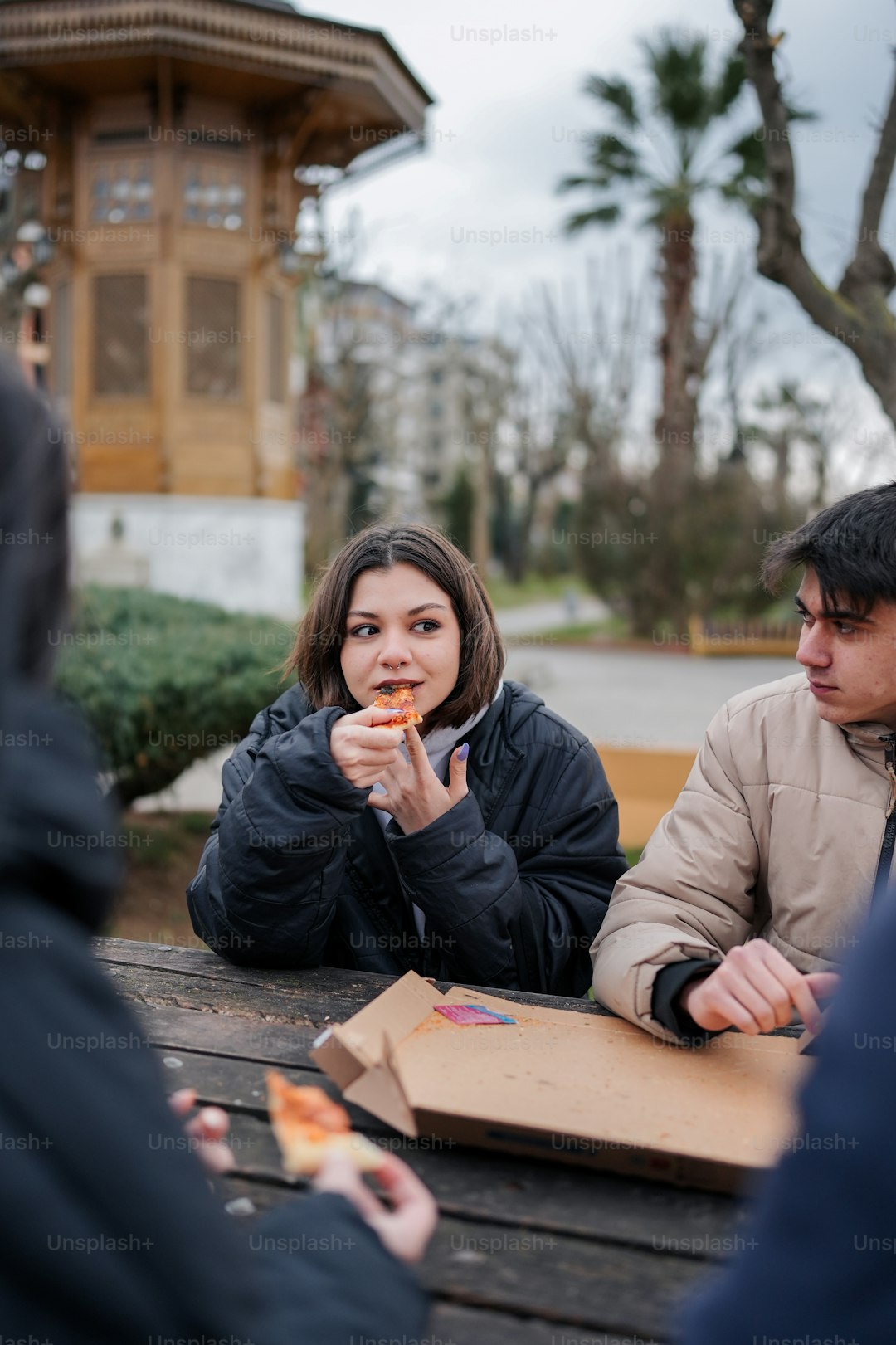 a group of people sitting at a picnic table eating pizza