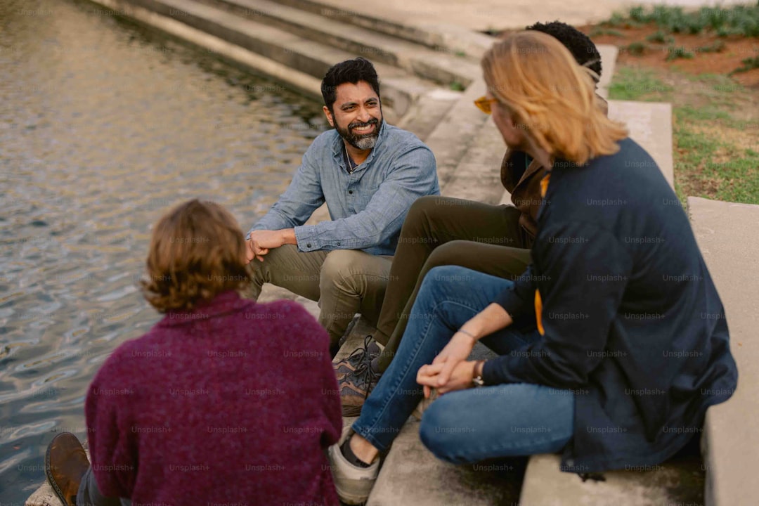 a group of people sitting next to a body of water