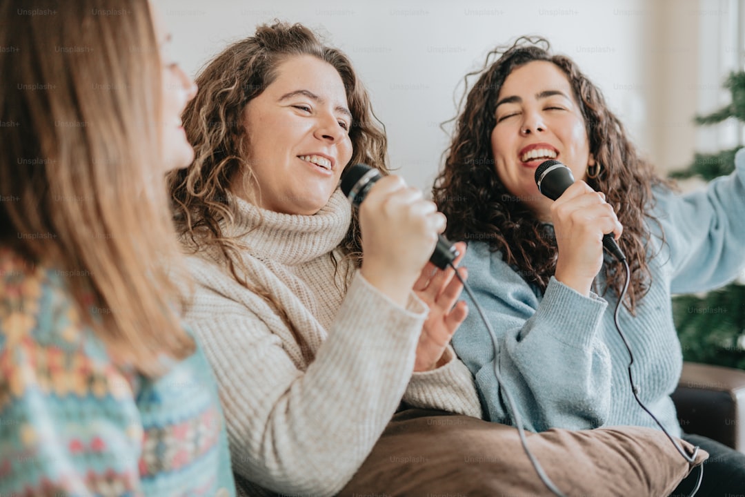 a group of women singing into microphones while sitting on a couch