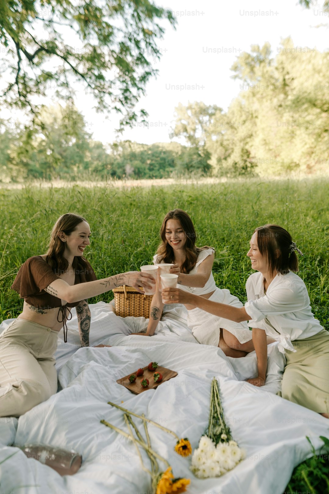 a group of women sitting on top of a lush green field