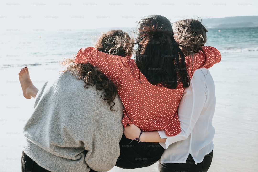 a group of women standing next to each other on a beach