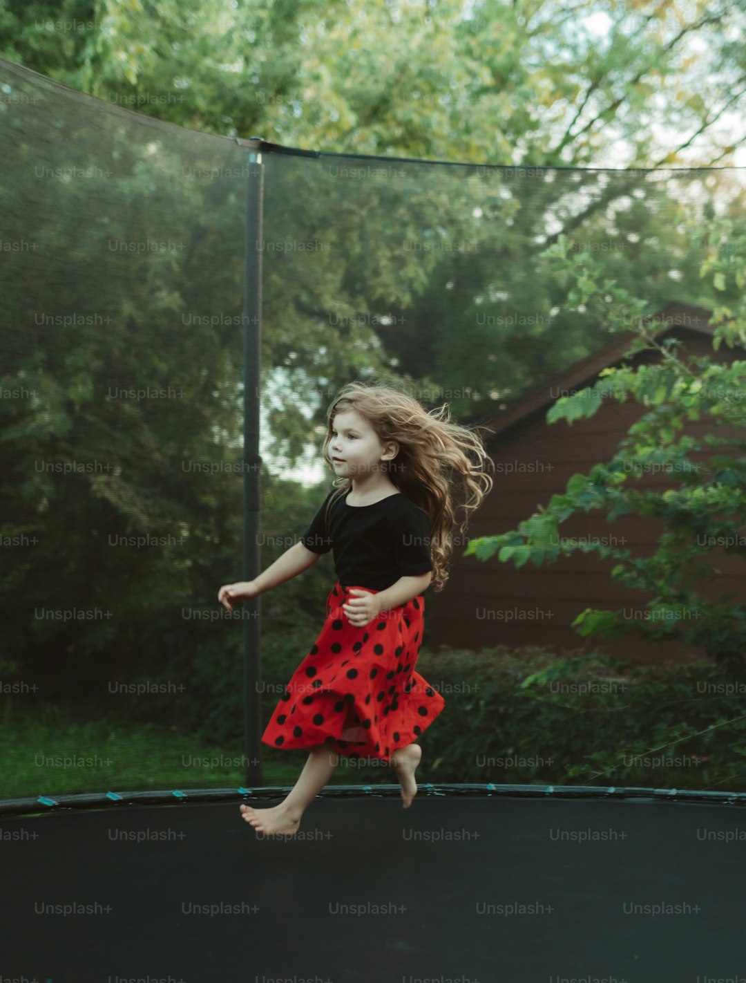 a little girl is jumping on a trampoline