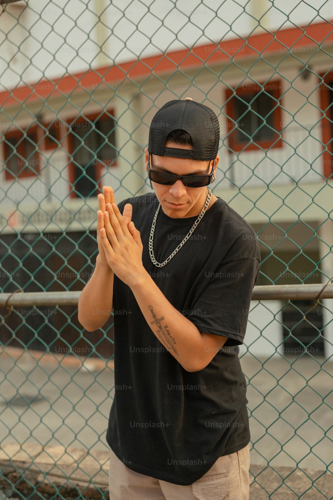 a man in a black shirt and a chain link fence