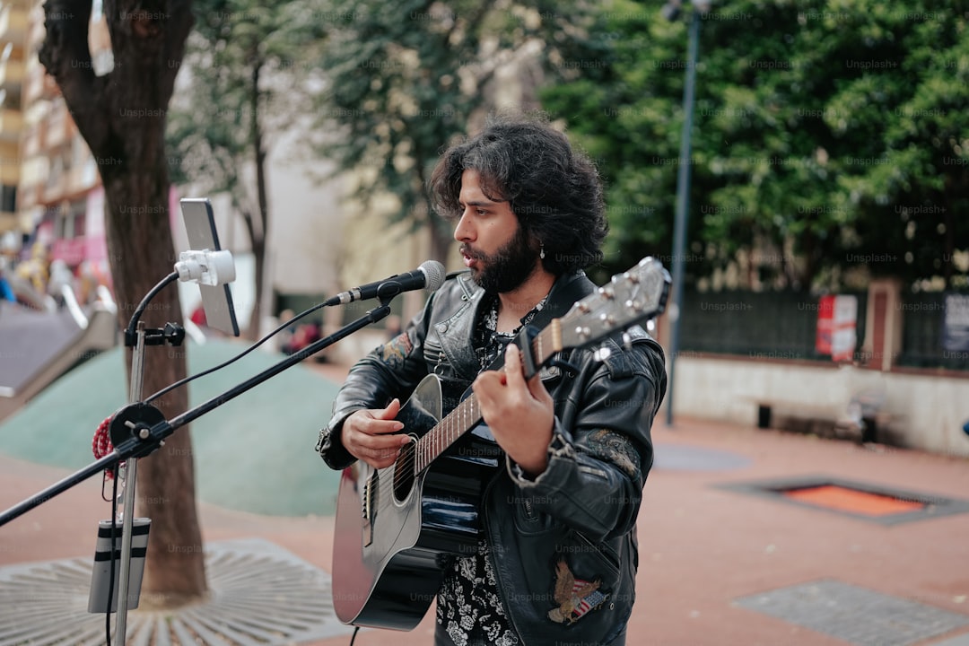 a man playing a guitar in front of a microphone