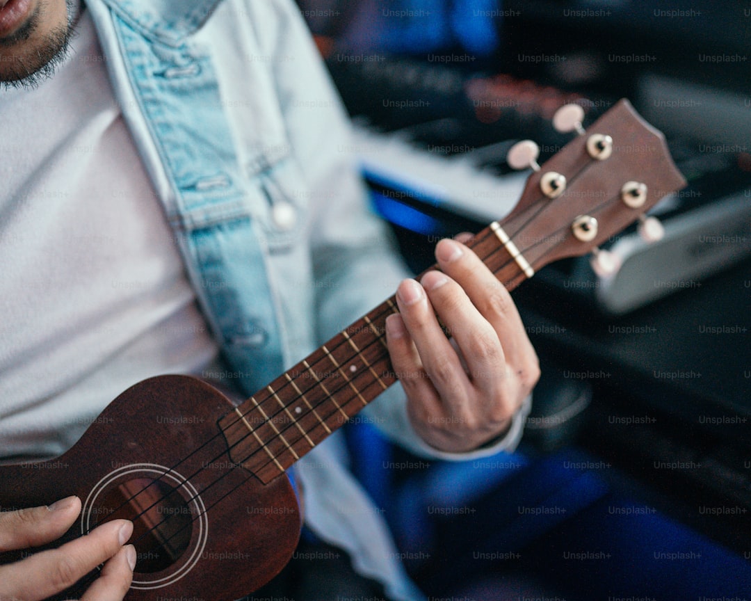 a man playing a ukulele in front of a keyboard