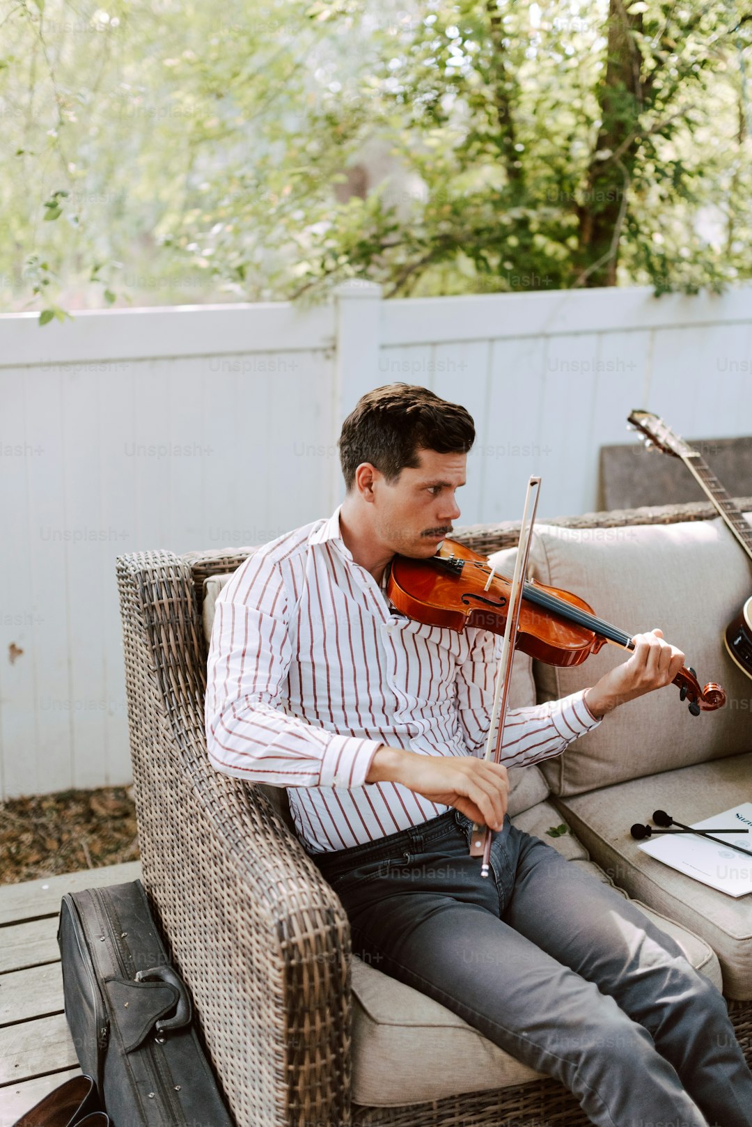 a man sitting on a couch playing a violin