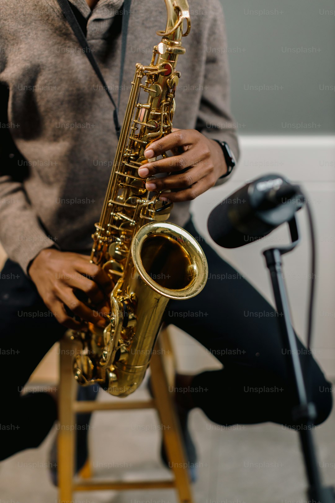 a man sitting on a stool holding a saxophone