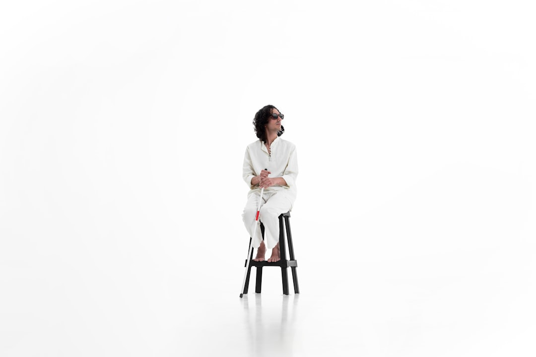 A man sitting on a stool in front of a white background