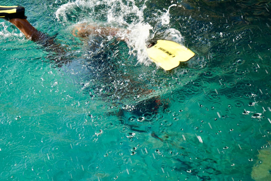 A man swimming in the water with a yellow board