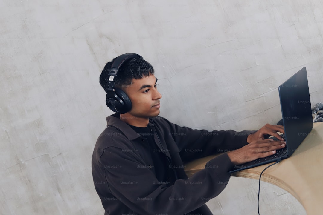 A man wearing headphones using a laptop computer