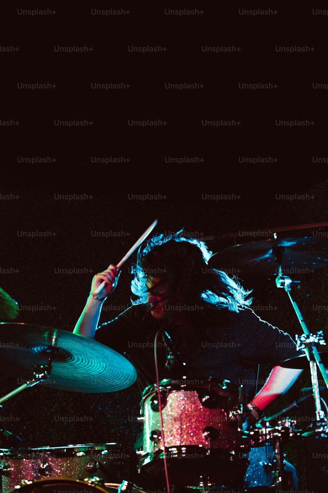 a man with long hair playing drums on a stage