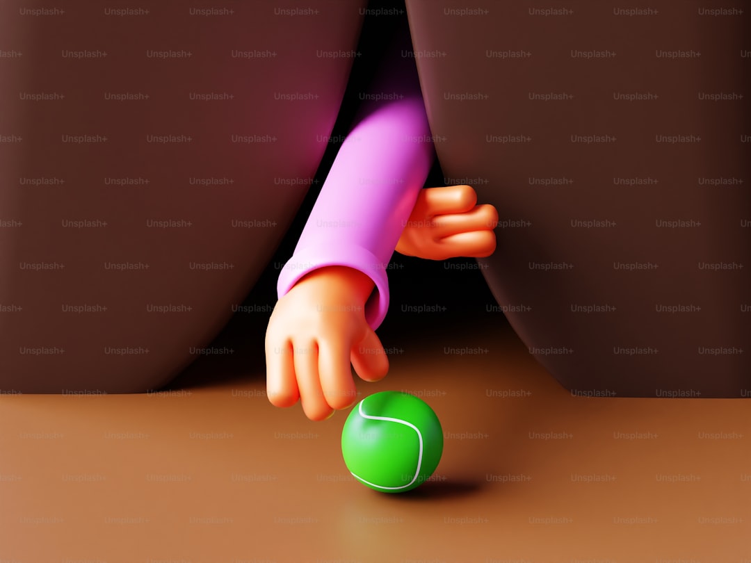 A person reaching for a green ball on the ground