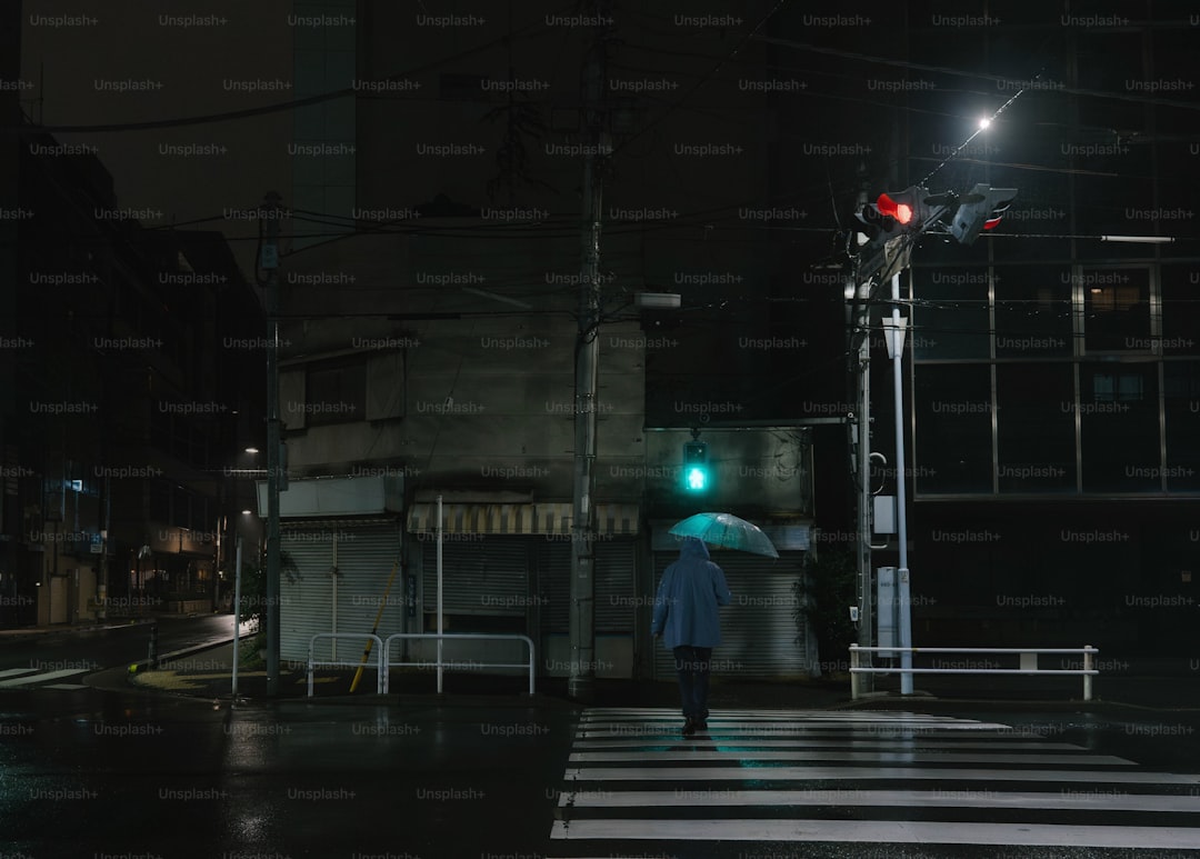 A person walking across a street holding an umbrella