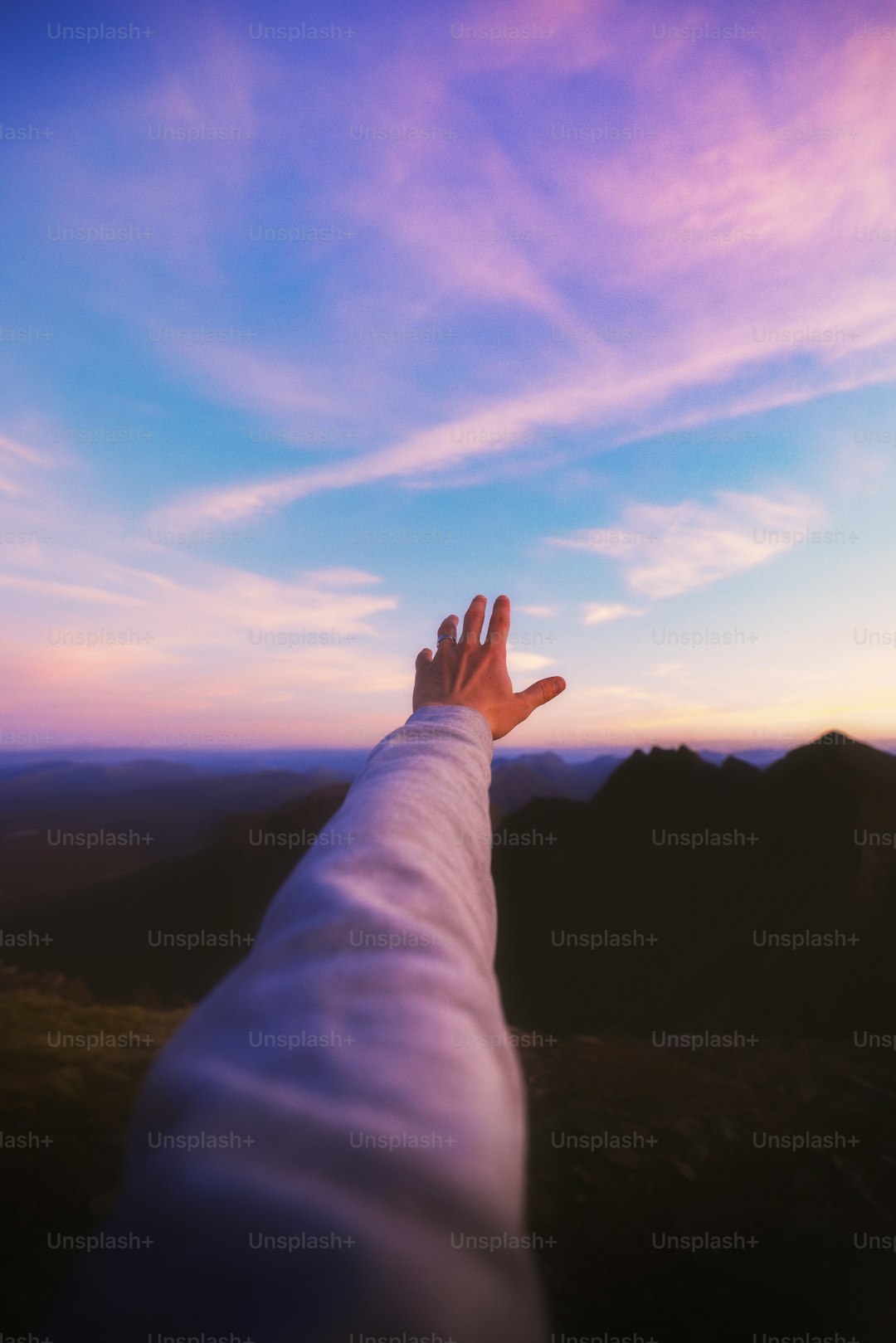 A person's hand reaching up into the sky