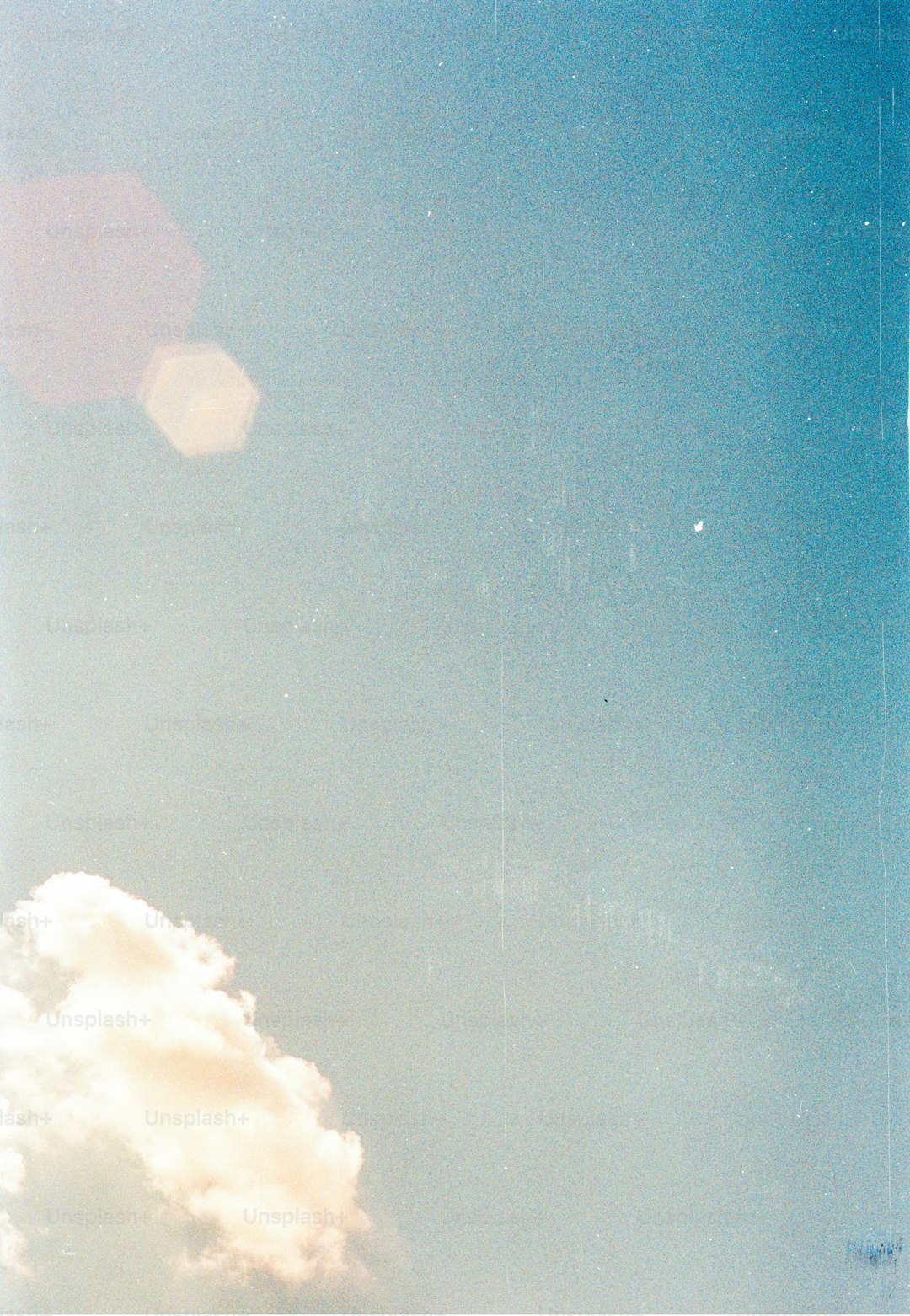 a plane flying through a blue sky with clouds