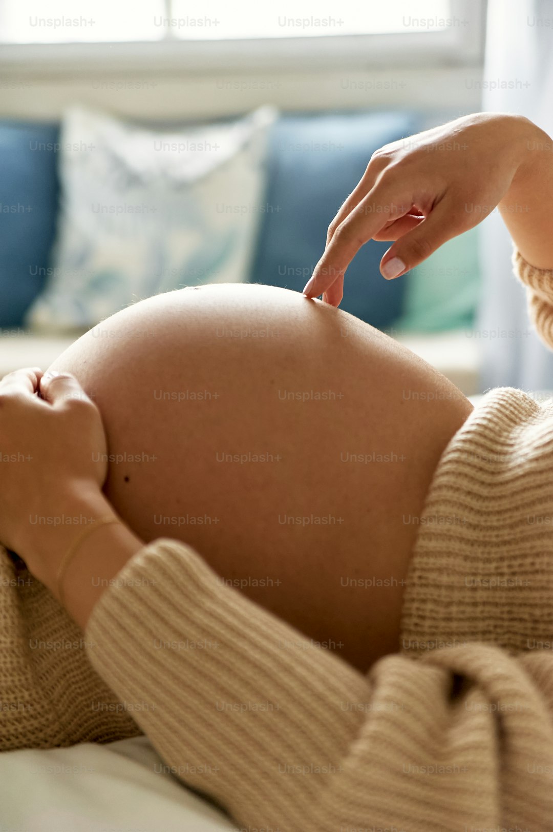 a pregnant woman laying on a bed touching her belly