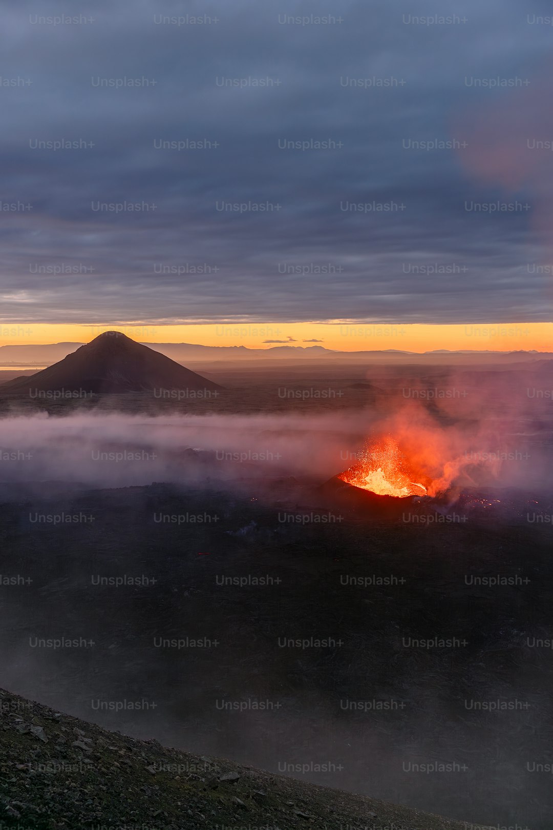 a volcano spewing out lava in the distance