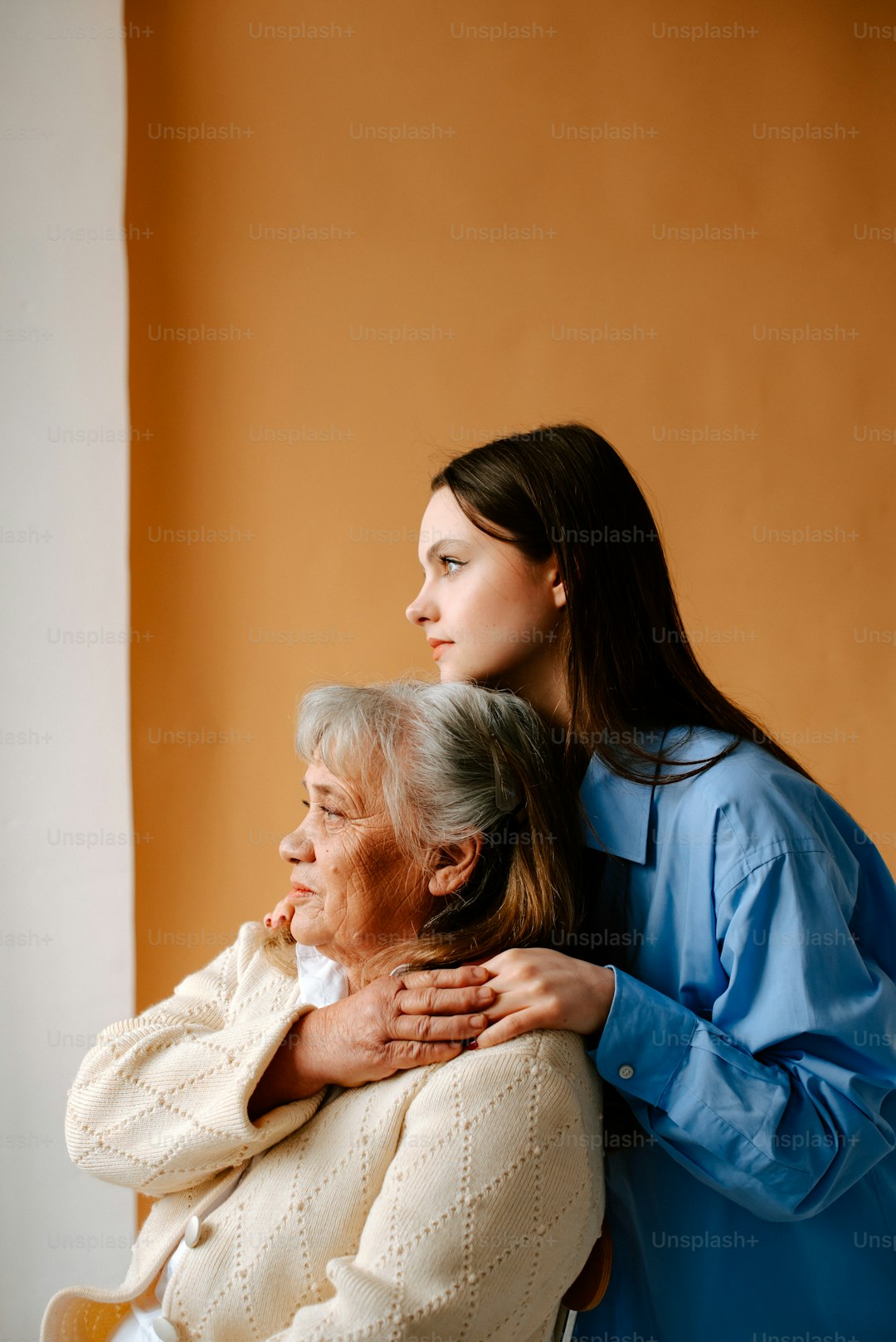 a woman hugging a woman who is sitting on a chair