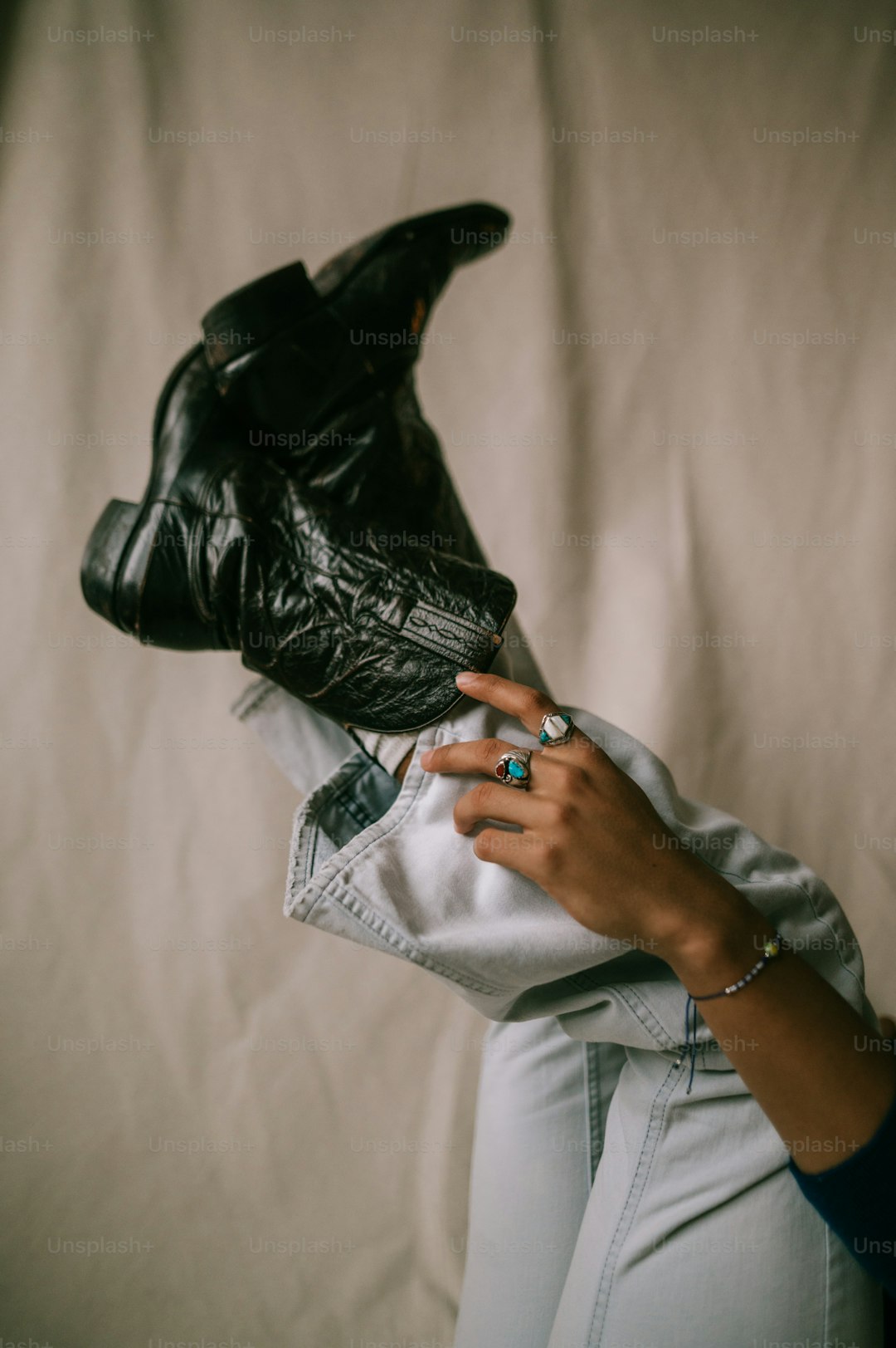 a woman is holding a pair of black boots