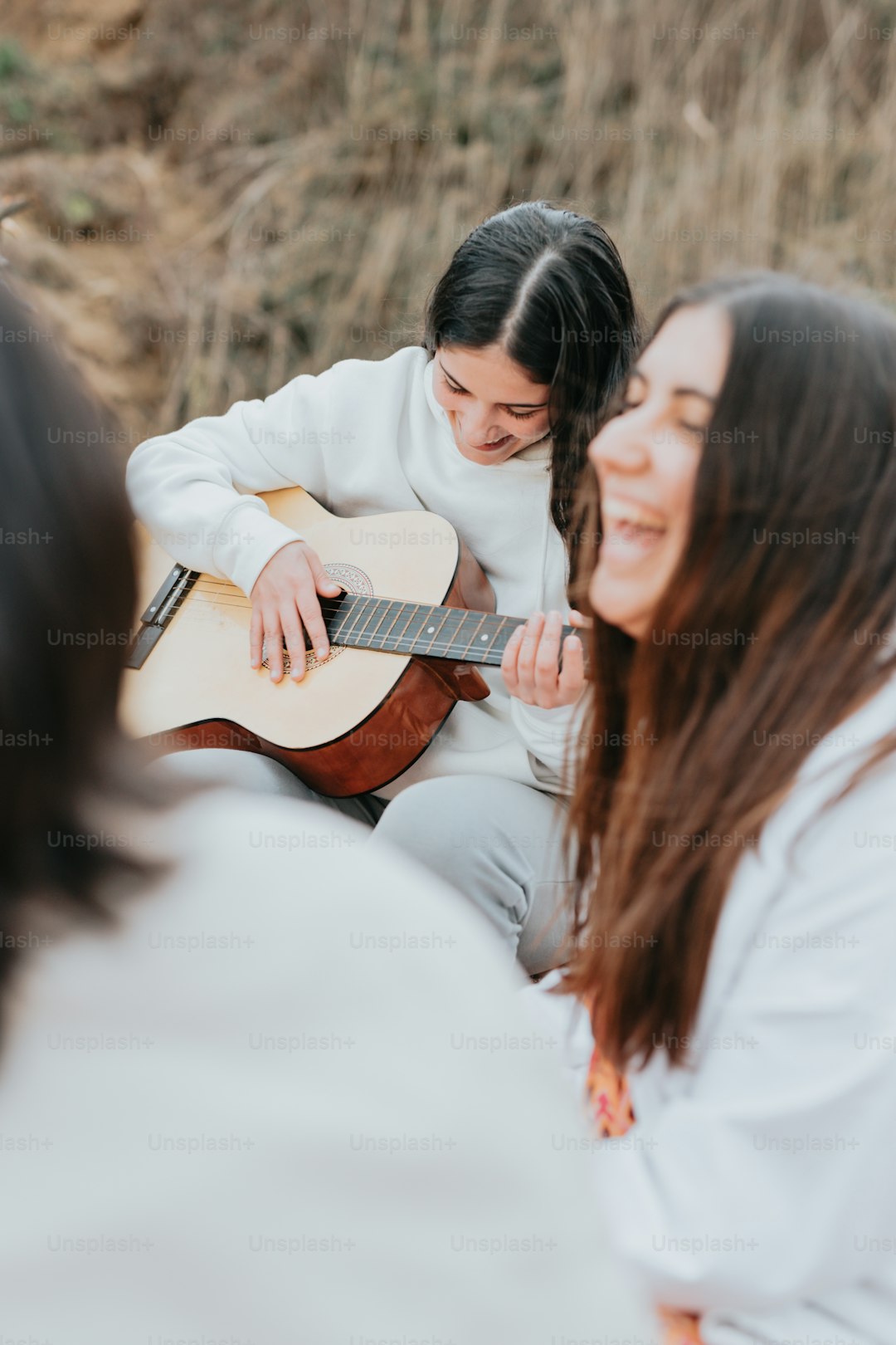 a woman playing a guitar while another woman looks on