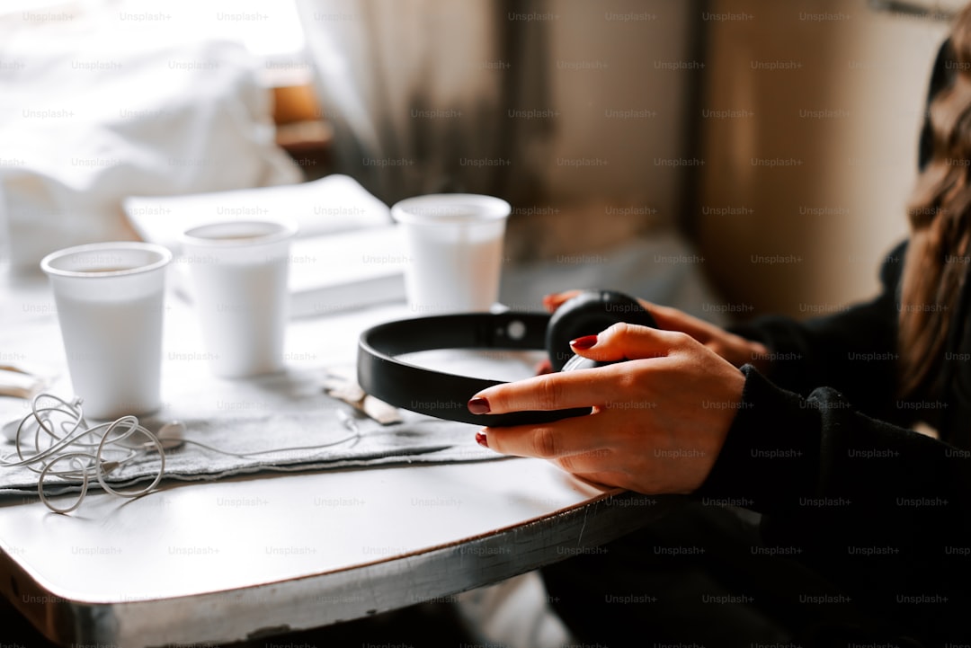 a woman sitting at a table holding a black object