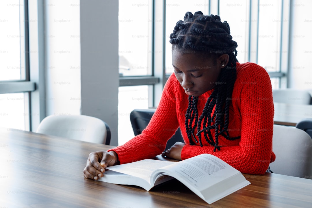 a woman sitting at a table reading a book