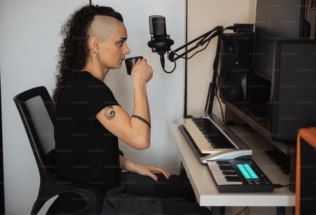 a woman sitting in front of a keyboard drinking a cup of coffee