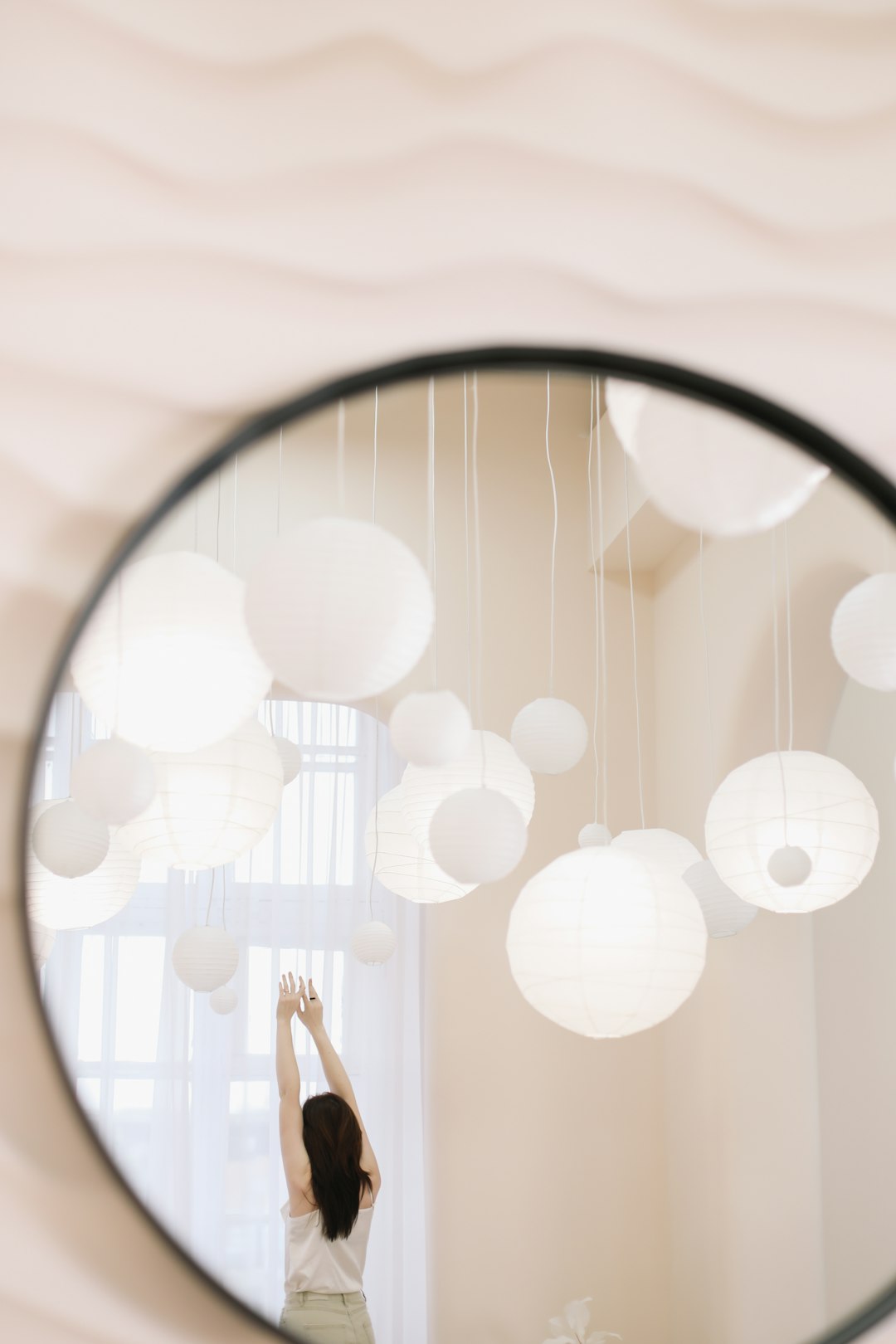 a woman standing in front of a round mirror