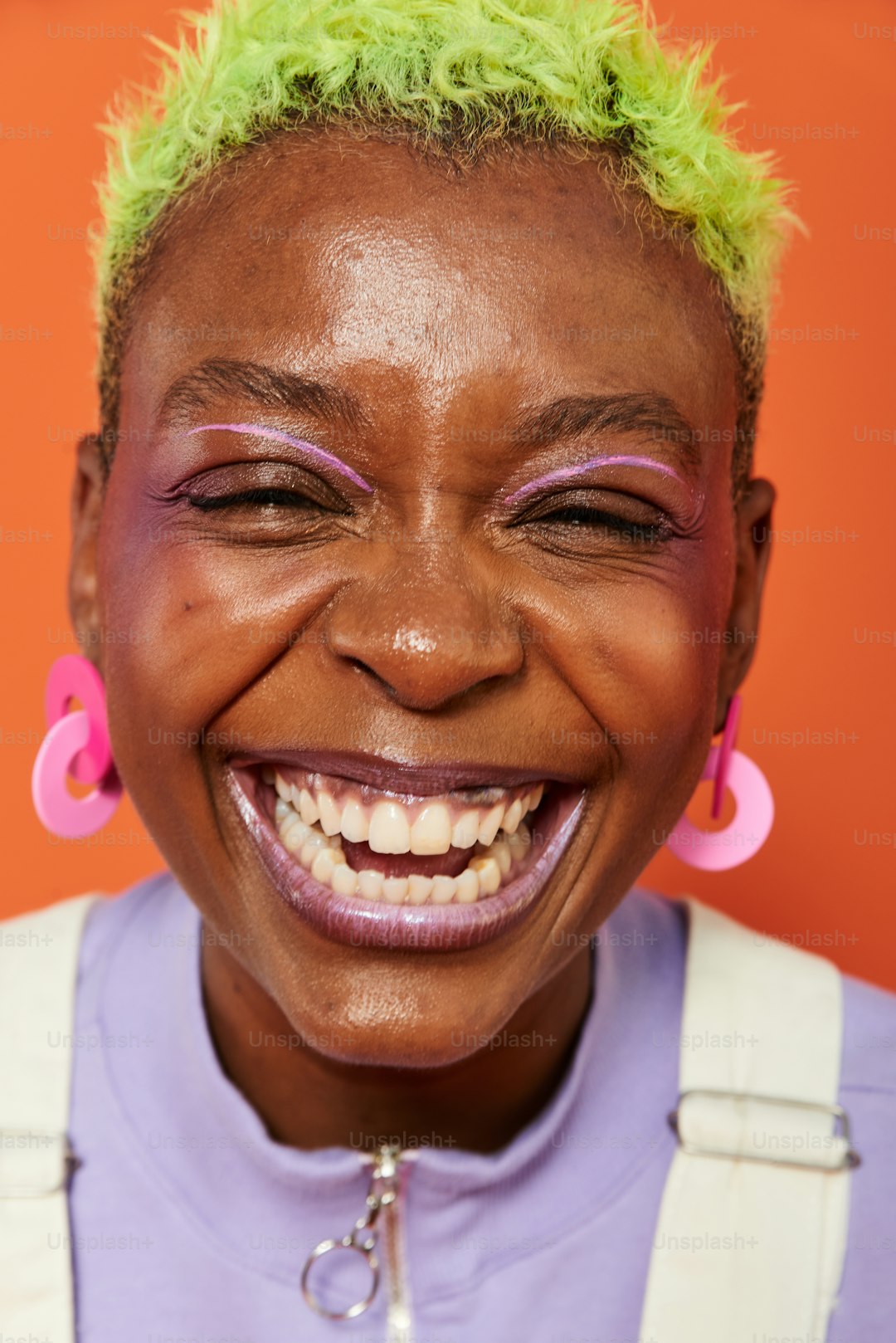 a woman with bright green hair and pink earrings