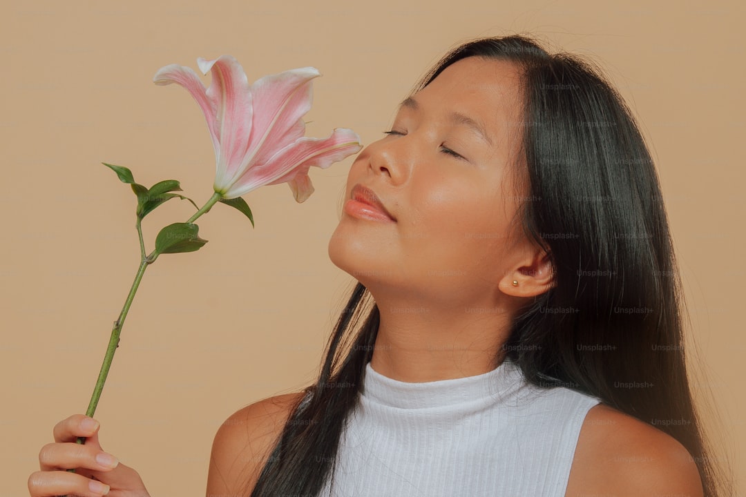 a young girl smelling a pink flower with her eyes closed