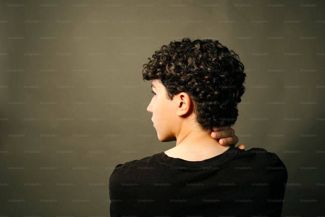 A young person with curly hair looks away.