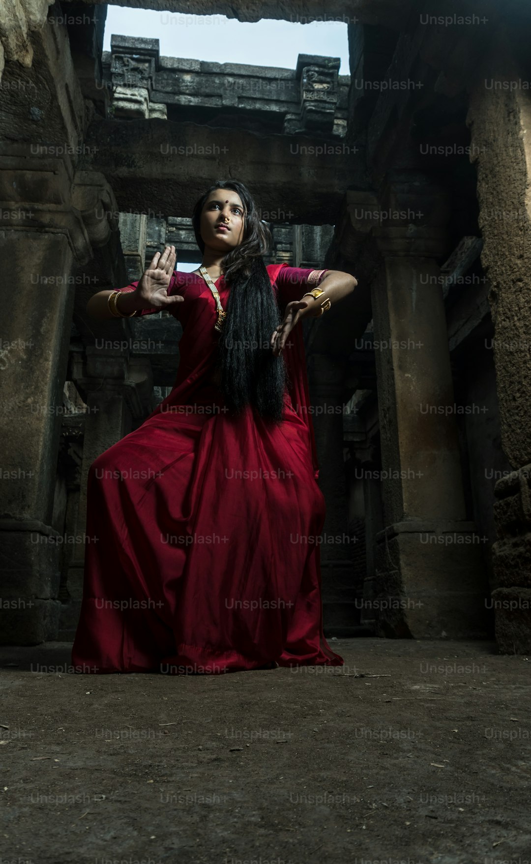 Beautiful indian girl dancer in the posture of Indian dance . Indian classical dance bharatanatyam. Girl wearing traditional Indian red saree, gold jewellery and bangles.Maa Durga shoot concept