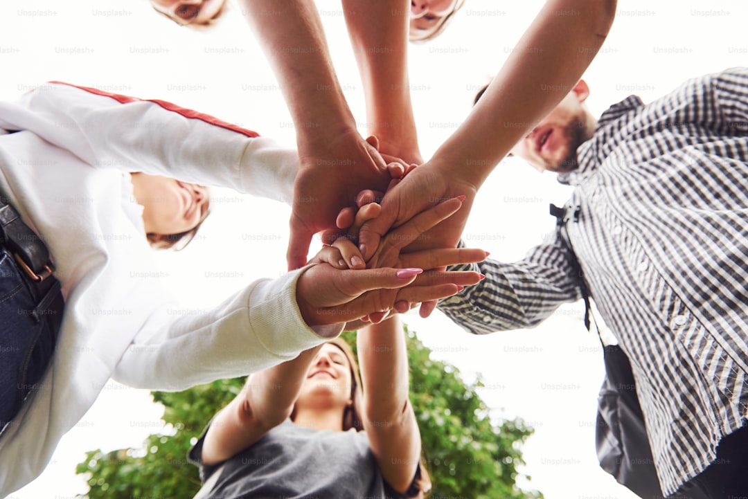 Close up view of hands of the young team of successful friends outdoors.